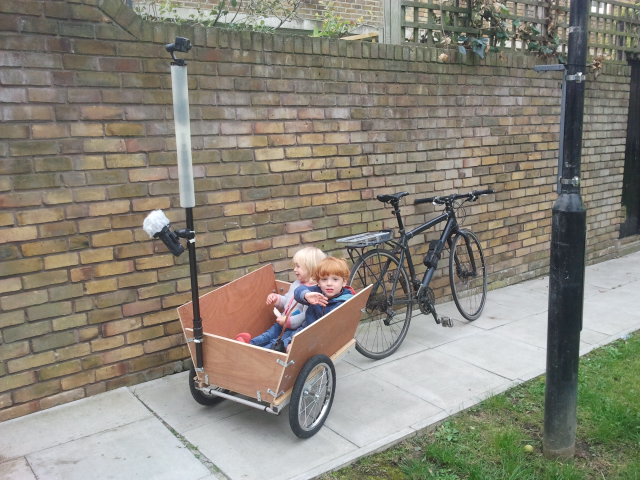 Smiling kids in a prototype wooden bike trailer